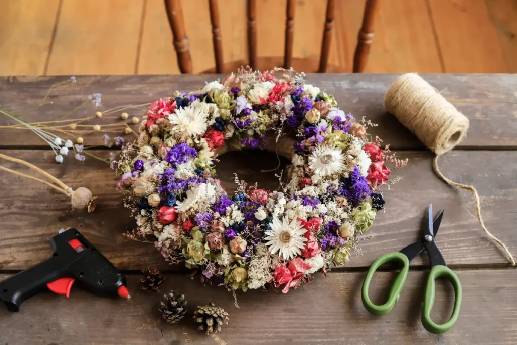 Auf einem Holztisch liegt ein selbst gebastelter Blumenkranz aus getrockneten Blumen.
