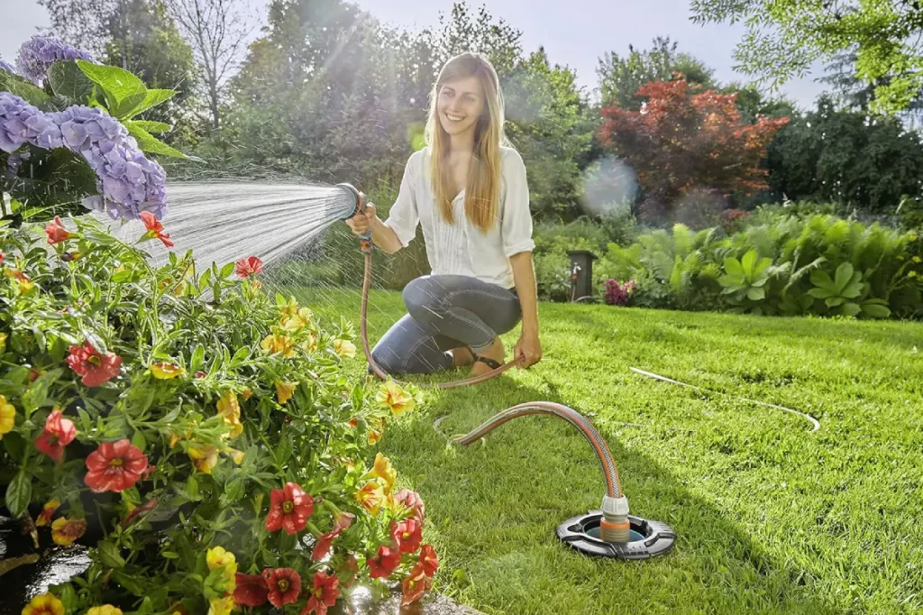 Eine Frau schließt den Gartenschlauch an eine Wassersteckdose an.