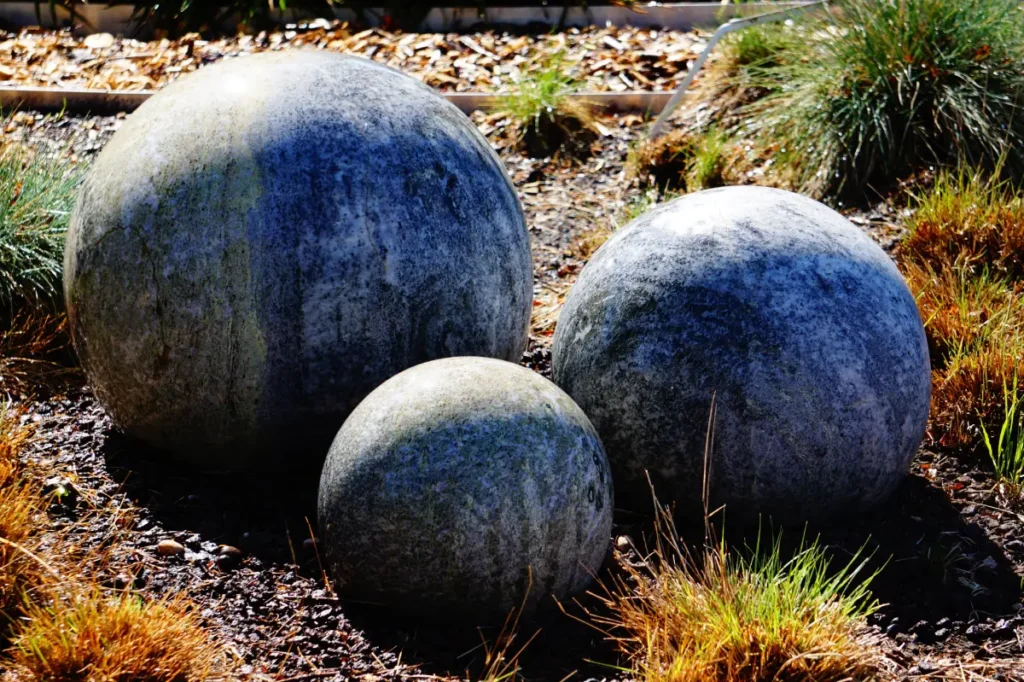 Stein-Gartenkugeln in einem Beet.