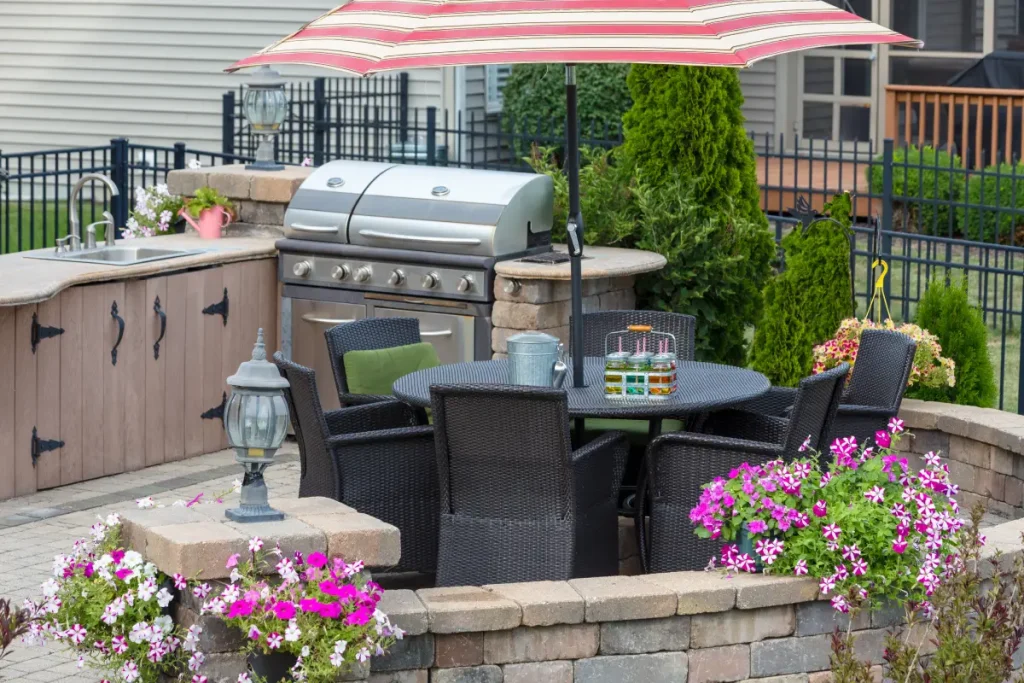 Terrasse mit Rattan-Sitzgruppe und gemauerter Gartenküche.