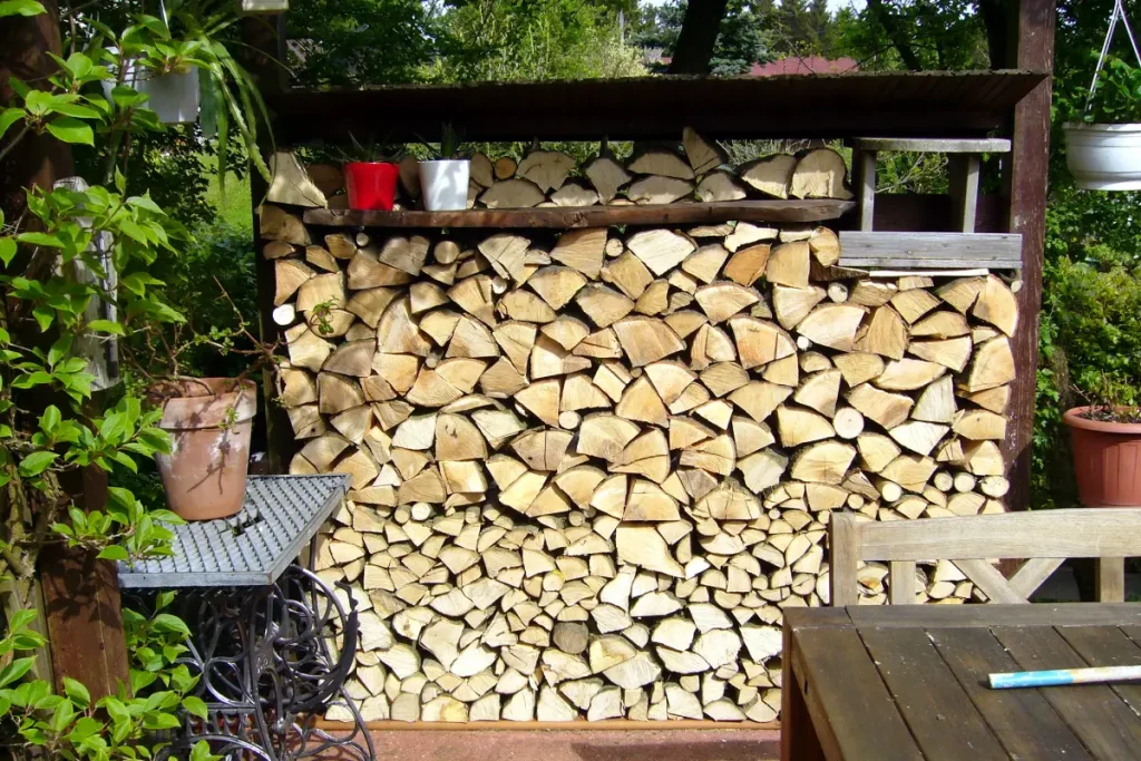 Gestapeltes Brennholz in einem Brennholzregal dient als Sichtschutz auf der Terrasse.