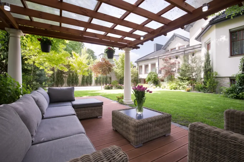 Gemütliche Rattan-Lounge unter einer Pergola mit Gartenblick.