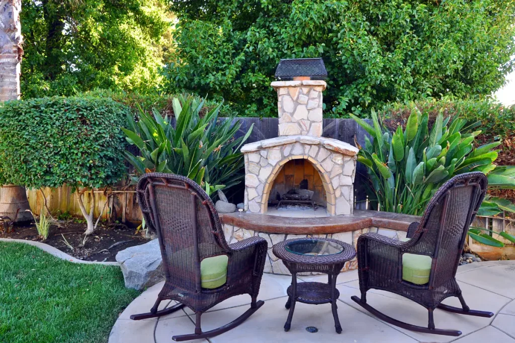 Kleine Terrasse mit zwei Schaukelstühlen vor einem urigen Kamin.