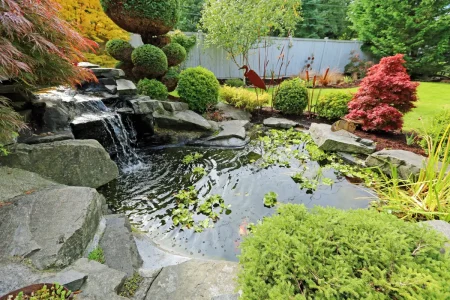 Kleiner Teich mit Wasserfall schafft Höhe und Sichtschutz im Garten.