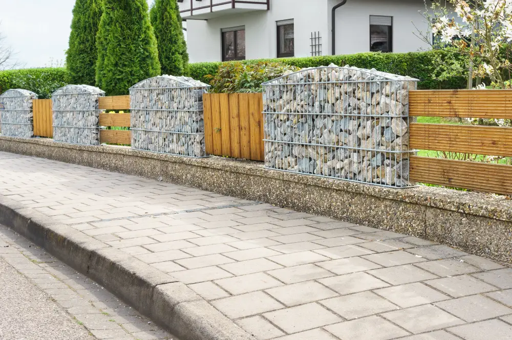 Gartenzaun aus Holzelementen und Gabionen.
