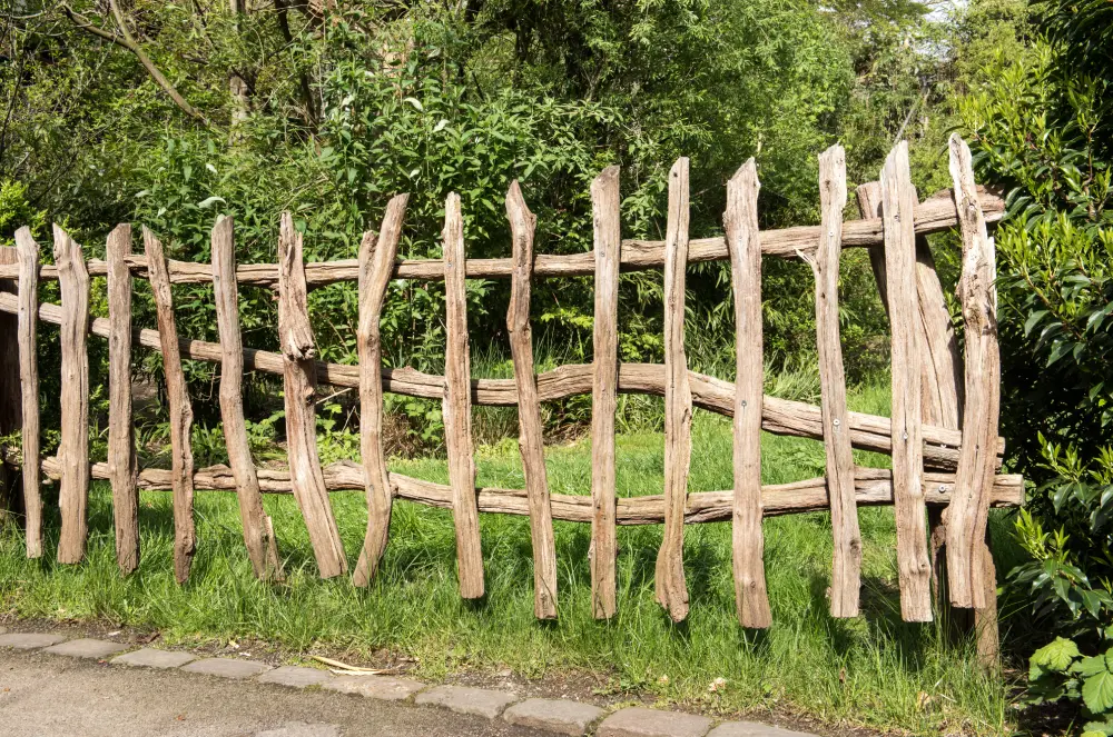 Gartenzaun aus dicken, naturbelassenen Ästen.