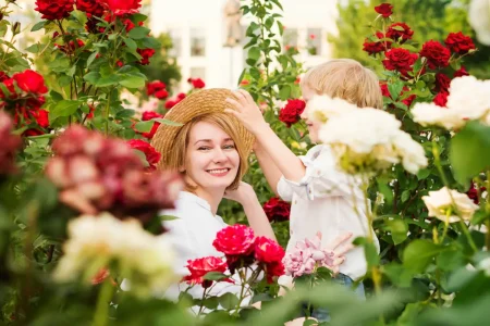 Mutter und Kind hocken im Rosenbeet.