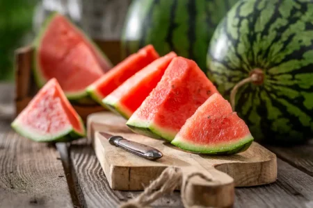 Geschnittene Melonendreiecke liegen auf einem Holzbrett.