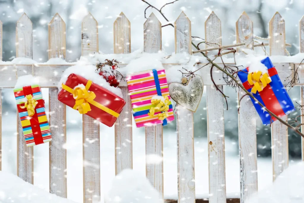 Bunte Geschenke hängen dekorativ am Gartenzaun.