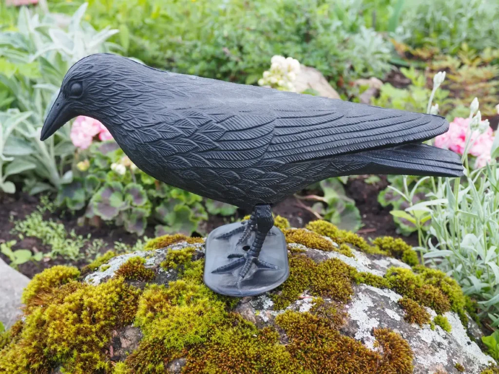 Kunststoffrabe auf einem Stein im Garten Schwalben vertreiben