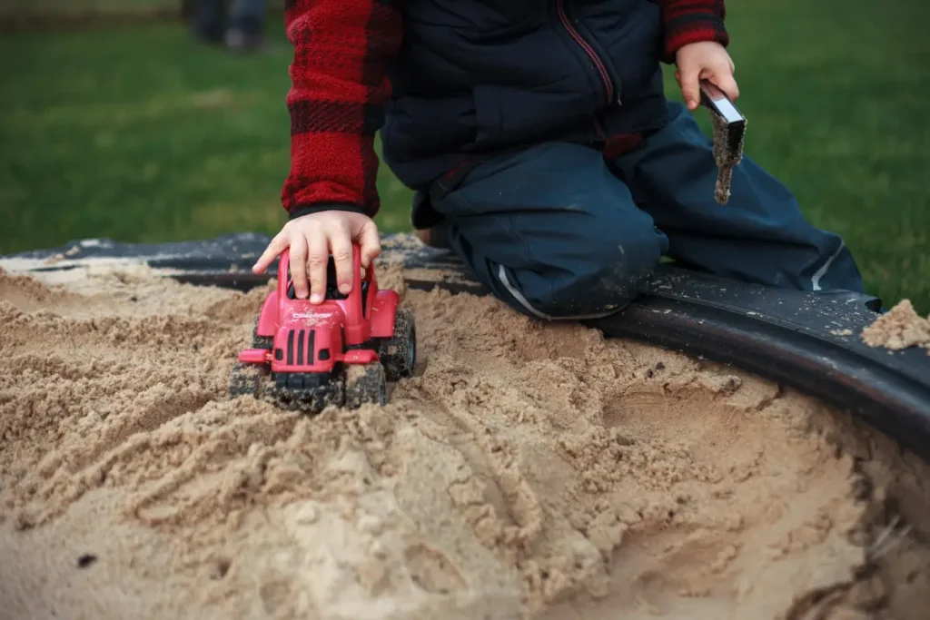 Kind spielt mit einem Traktor im Sandkasten Gartenspielzeug: 8 einfache DIY-Ideen für Ihre Kinder