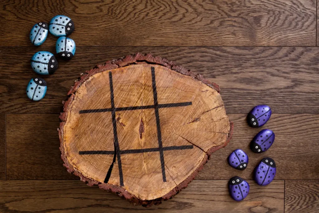 Tic Tac Toe aus einer Baumscheibe und bemalten Steinen Gartenspielzeug: 8 einfache DIY-Ideen für Ihre Kinder