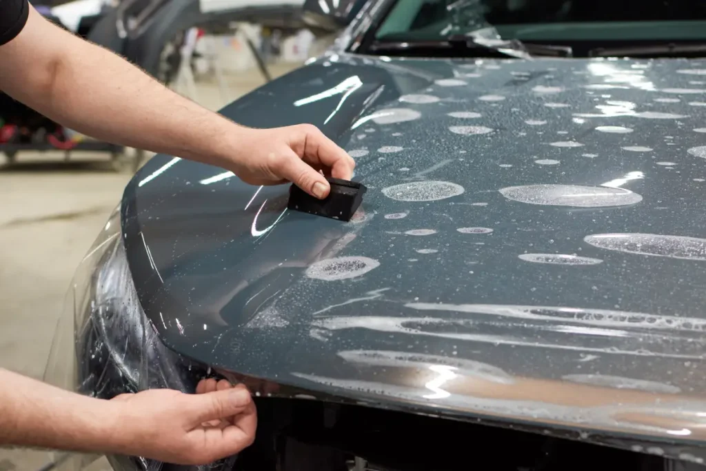 Mann befestigt eine Schutzfolie auf der Motorhaube eines Autos Von Schutz bis Dekoration: Wie Sie die ideale Folie für Ihre Anforderungen finden