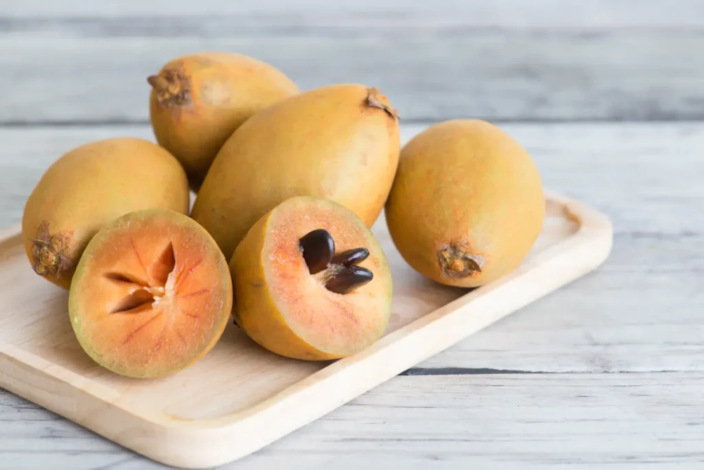 Aufgeschnittener Breiapfel neben ganzen Früchten Breiapfelbaum pflanzen, pflegen und überwintern